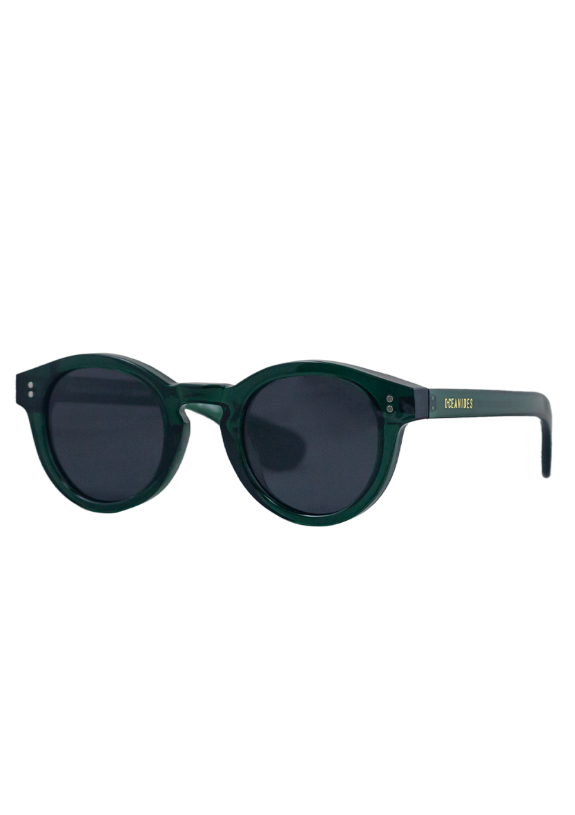 Rodea Crystal Green Sunglasses by Oceanides feature round, dark green polarized lenses, black accents, a recycled plastic frame, and "OCEANIDES" in gold on the right arm, shown on a plain white background.