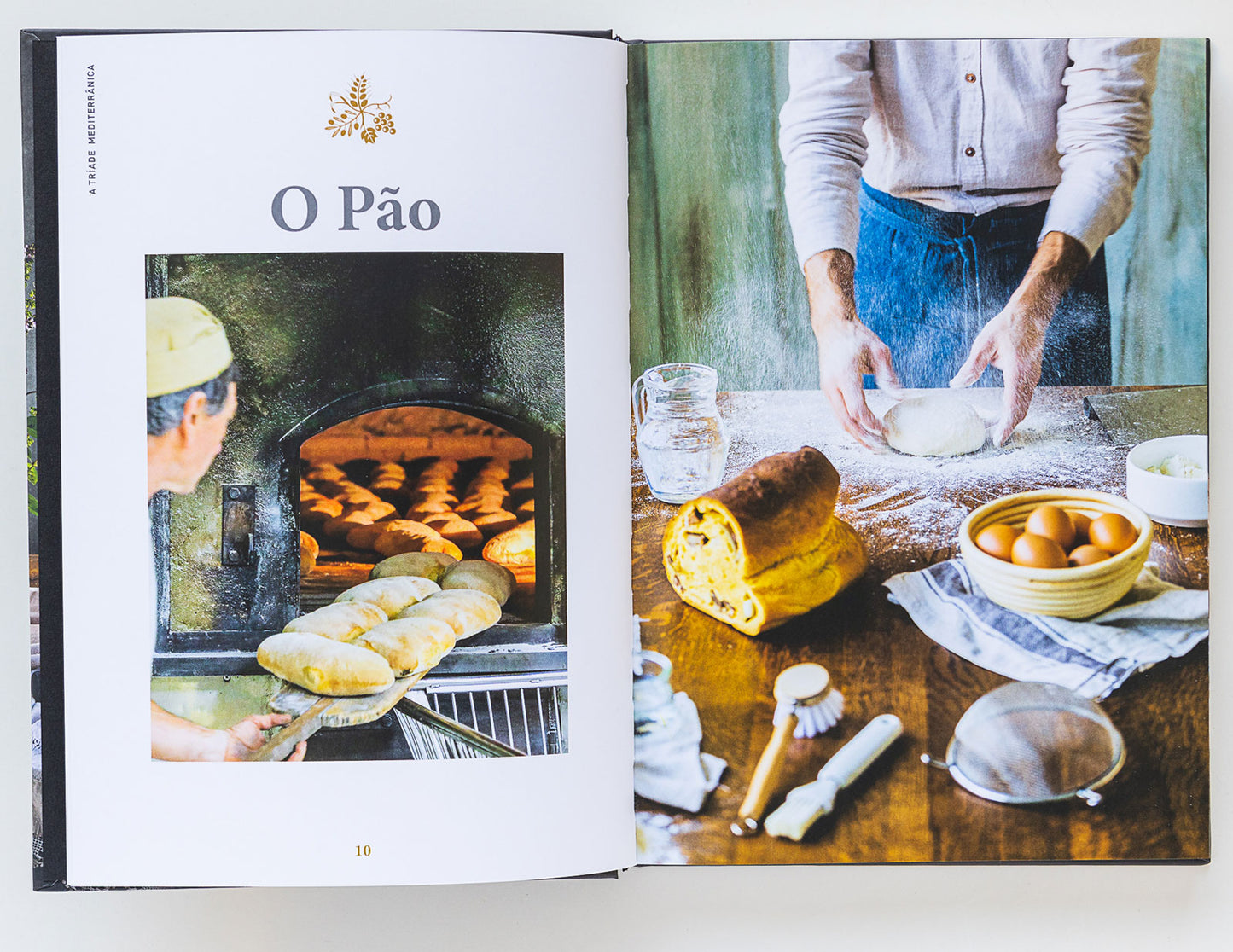 An open cookbook features Bread, Olive Oil & Wine by ObjectoAnonimo—a baker placing bread in a wood-fired oven and hands shaping dough with eggs, flour, water, and olive oil—ideal for the Mediterranean diet.
