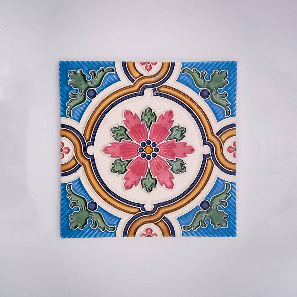 The Tejo Shop Decorative Fireplace Tiles showcase a hand-painted ceramic design with a central pink and green floral motif, blue accents, and an ornate circular border on a white background.