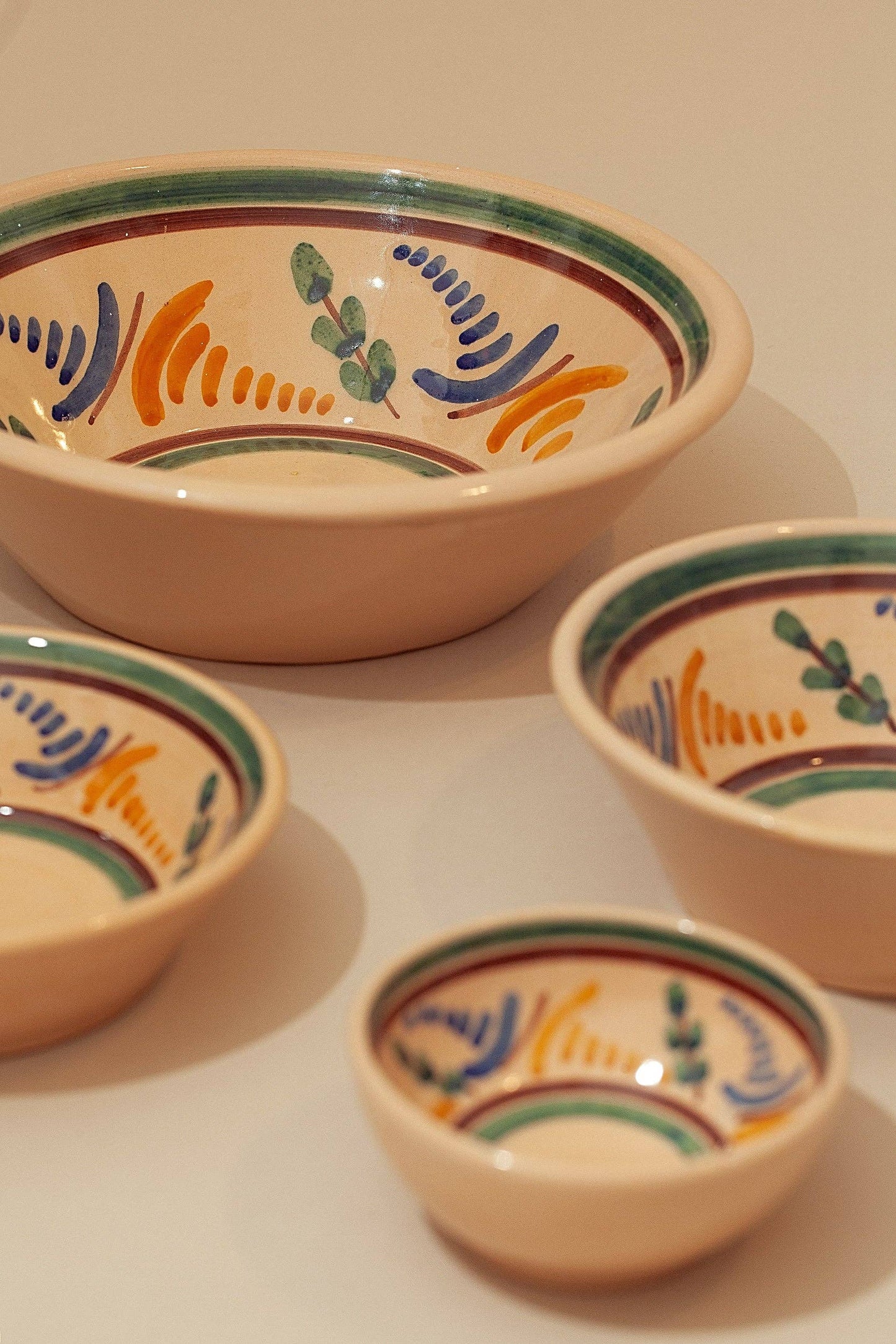 The Medina Printed Ceramic Bowls by Eturel Madrid feature colorful hand-painted Andalusian-inspired patterns in green, orange, blue, and brown. Each ceramic bowl has a cream-colored interior and rim, beautifully displayed together.
