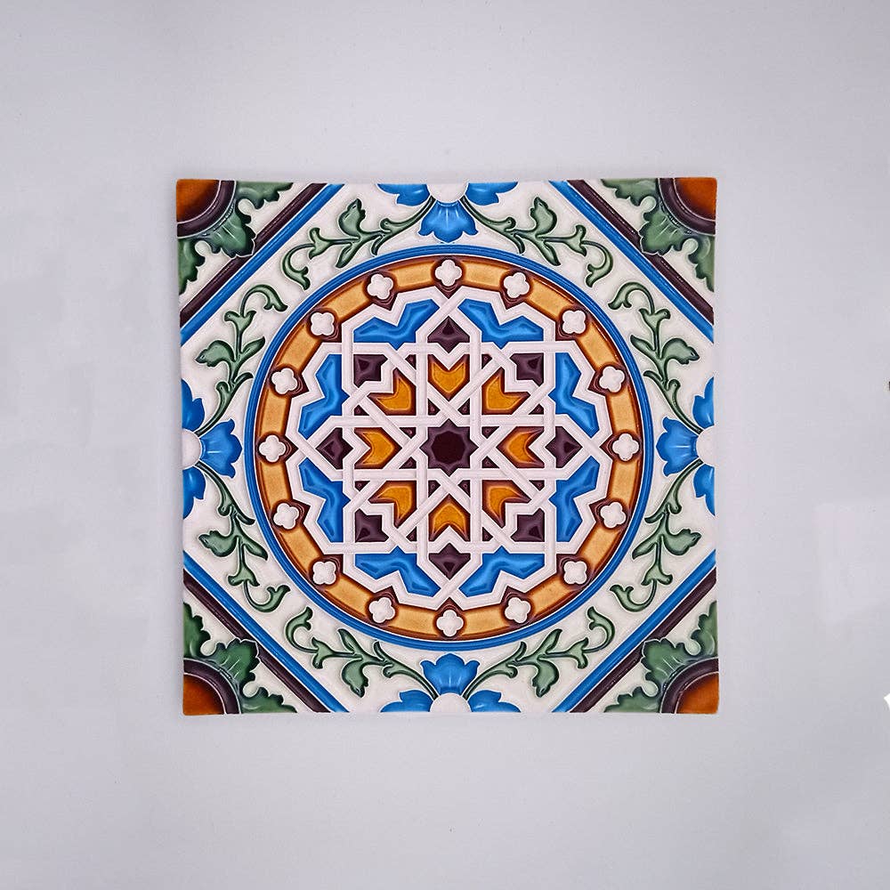 The Tejo Shop Mosaic Decorative Wall Tiles showcase a handcrafted ceramic tile with a detailed blue, green, orange, and brown geometric floral pattern—ideal as mosaic wall or backsplash tiles—on a plain light gray background.
