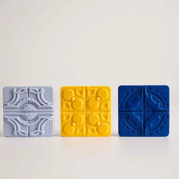 Three Portuguese Azulejo Scented Magnets by Manulena—light gray with a classic motif, yellow with abstract shapes, and blue with a circular design—are displayed side by side against a plain background.