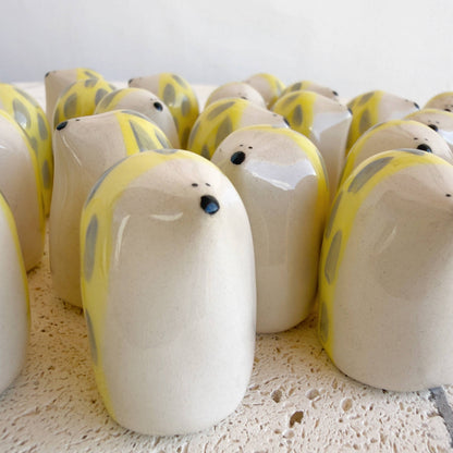 A cluster of Picuru ceramicas' Porcupine Amulet of Self-Protection—handmade ceramic figurines with cream bodies, yellow spots, and black noses—embody awareness and strength on a textured white surface.