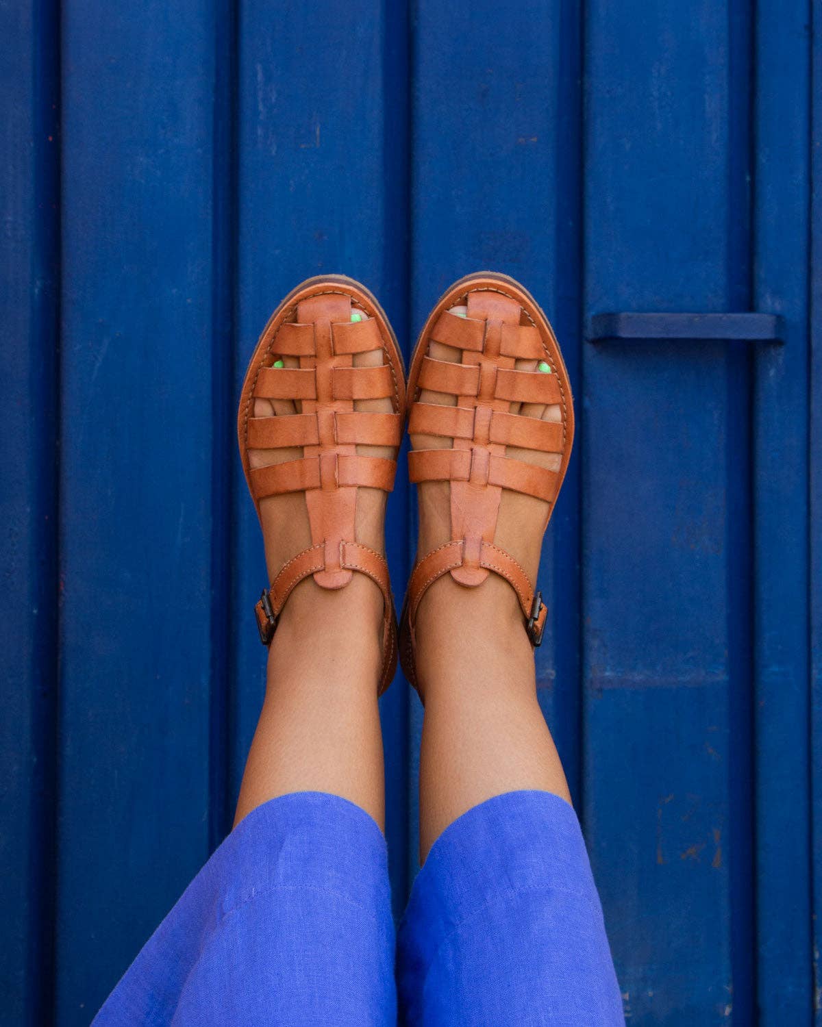 Brown strap sandals against a blue wall