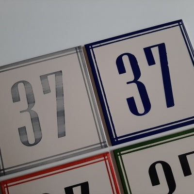 TilePassion’s Handpainted Ceramic Door Numbers – Custom Portuguese Tiles feature square tiles with “37” in gray, blue, and red borders, plus a “27” tile with a green border—evoking the look of classic Portuguese craftsmanship.