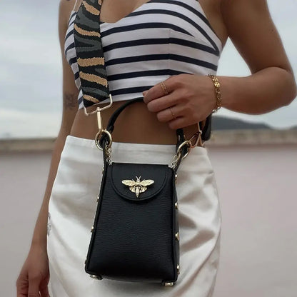 Lifestyle image of Black Bee bag worn crossbody using Zebra Green and Gold  strap.