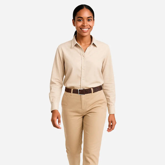A woman with dark hair tied back is smiling, wearing a beige button-up shirt and pants with the Corkor Womens Cork Belt – 30mm with Silver Buckle, standing against a plain light background.
