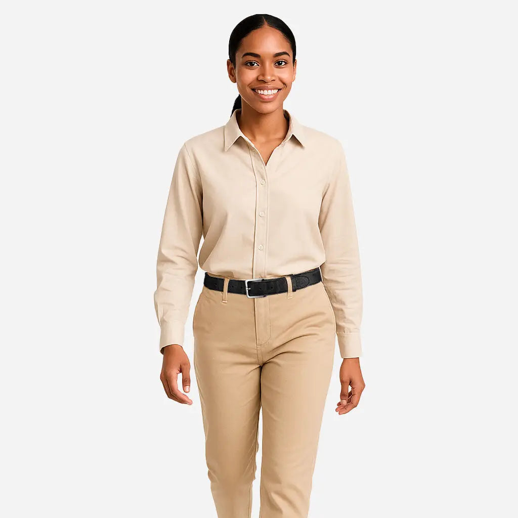 A woman smiles while standing against a white background, wearing a beige button-up shirt tucked into matching pants and accessorized with the Corkor Womens Cork Belt – 30mm with Silver Buckle.