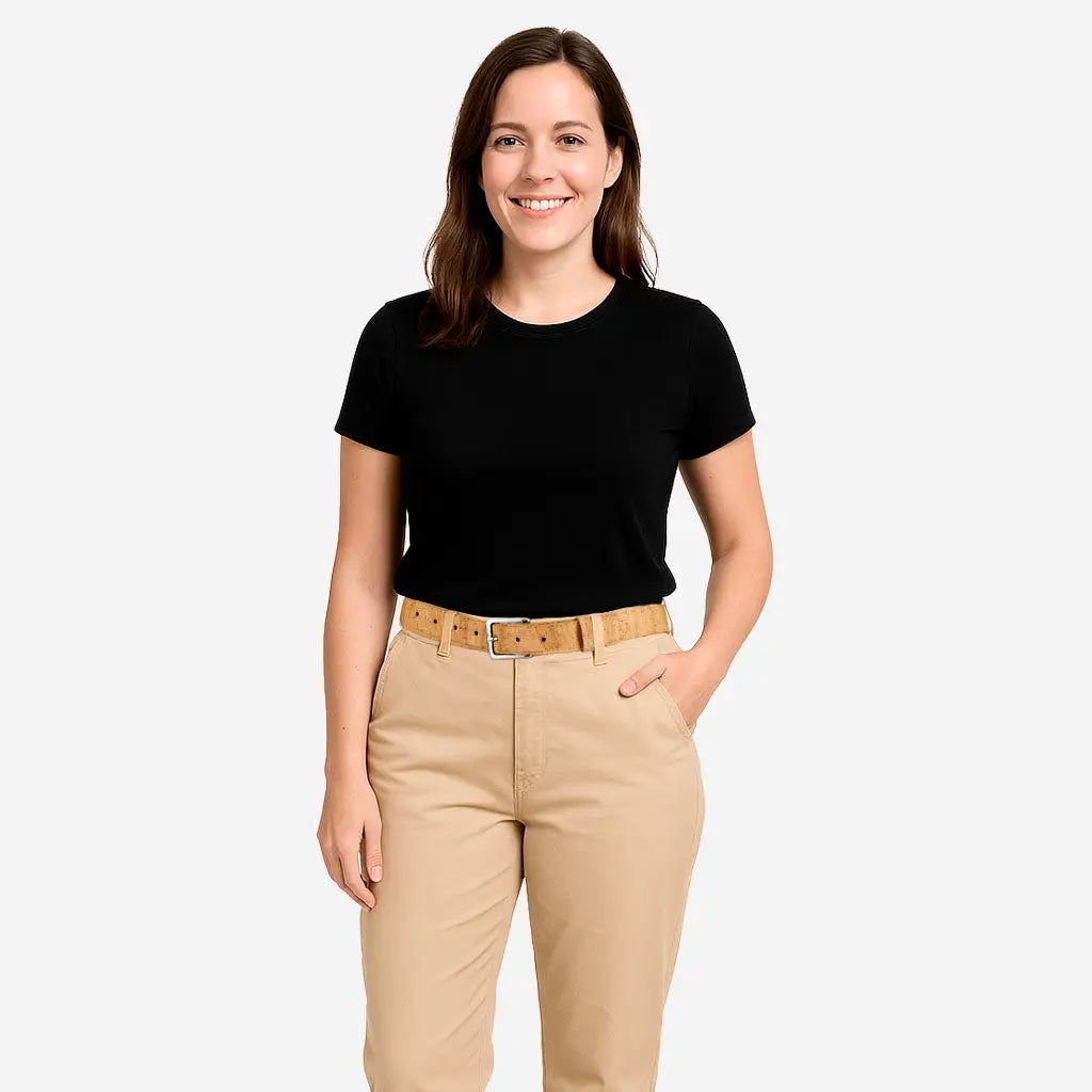 A woman with long brown hair smiles, wearing a black short-sleeve shirt and tan pants paired with the Corkor Womens Cork Belt – 30mm with Silver Buckle, standing against a plain white background.