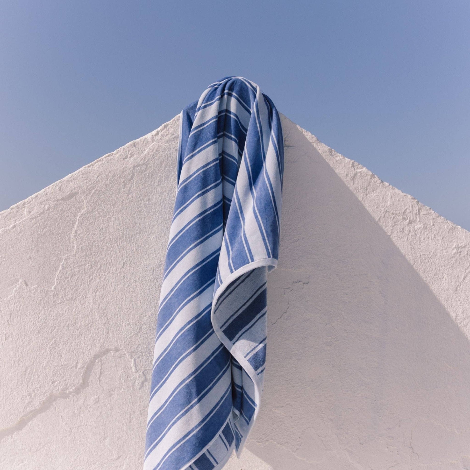 The Blue Meco Stripes Beach Towel 430 GSM by Torres Novas, made from 100% cotton and featuring blue and white stripes, brings classic Portuguese coastal style to any setting.