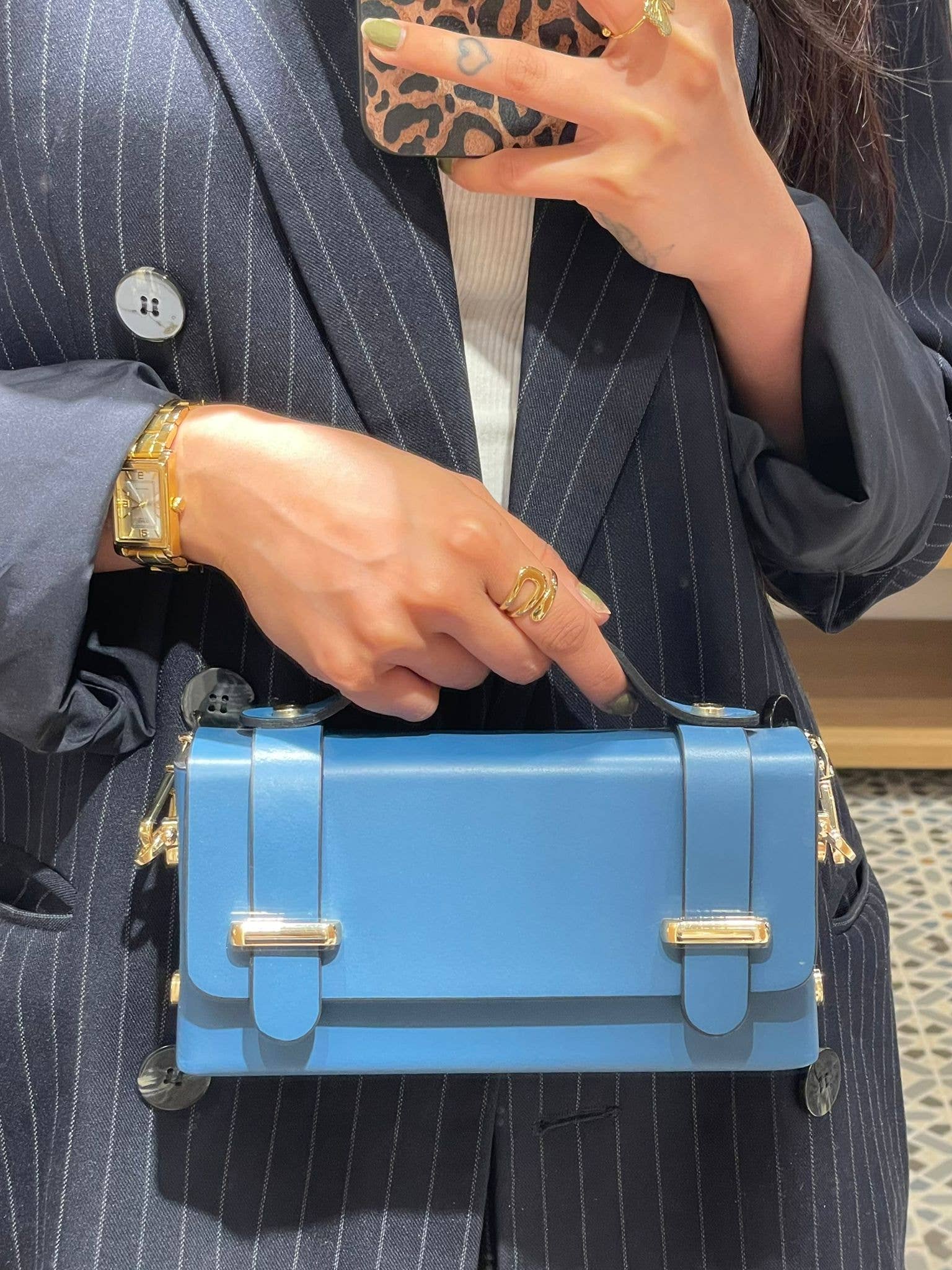 Lifestyle photo of the Carmel genuine leather bag in Blue being held by a model, showing size and top-handle detail.