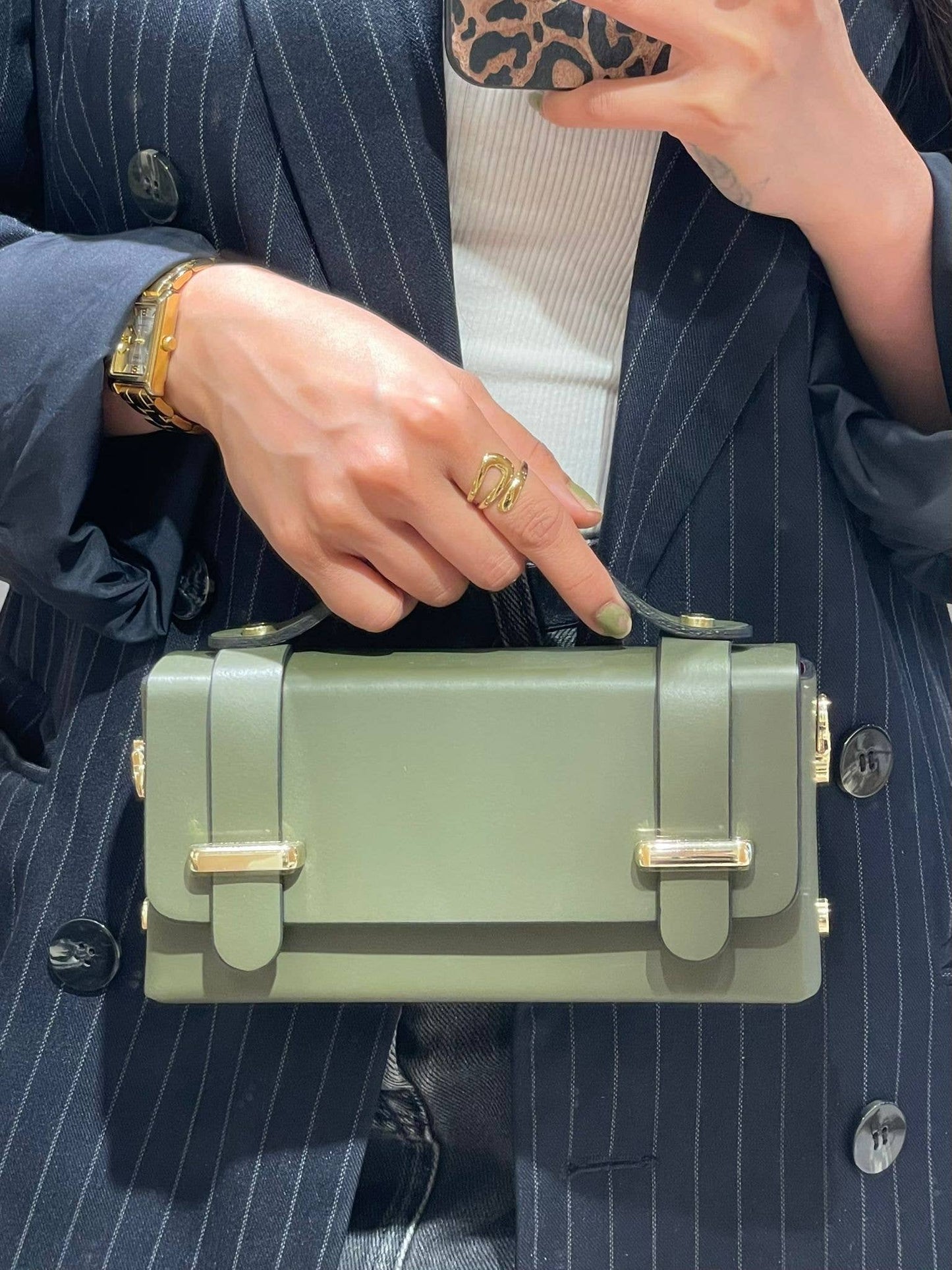 Lifestyle photo of the Carmel genuine leather bag in Khaki Green being held by a model, showing size and top-handle detail.