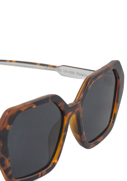Close-up of Oceanides Coral Dark Havana Sunglasses featuring oversized geometric frames in a tortoiseshell pattern and dark polarized lenses, displayed against a plain white background.