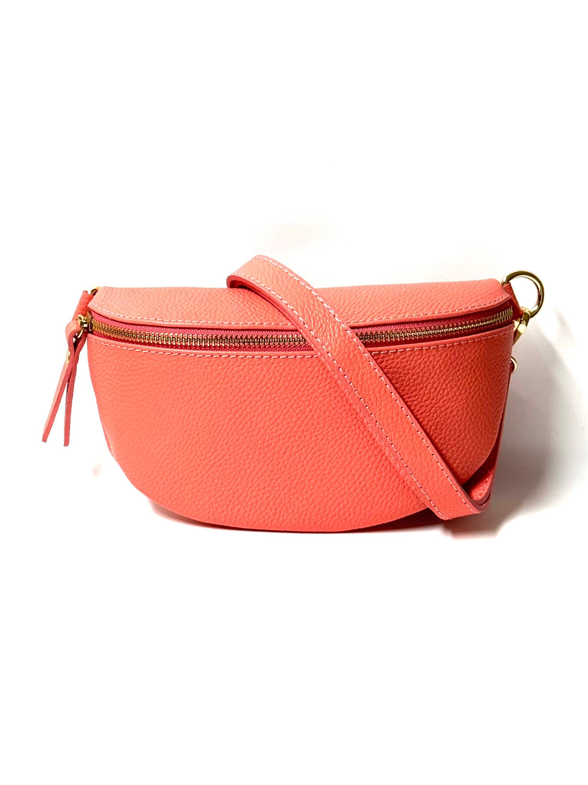 Cassette fanny pack/crossbody in coral Italian leather with gold zip and matching strap across front view on white.