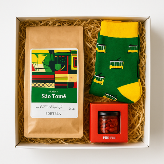 The Lisbon Essentials Box by Iberica includes São Tomé coffee, green and yellow tram-print Portuguese socks, and a mini piri-piri jar, all nestled in straw-like packing.
