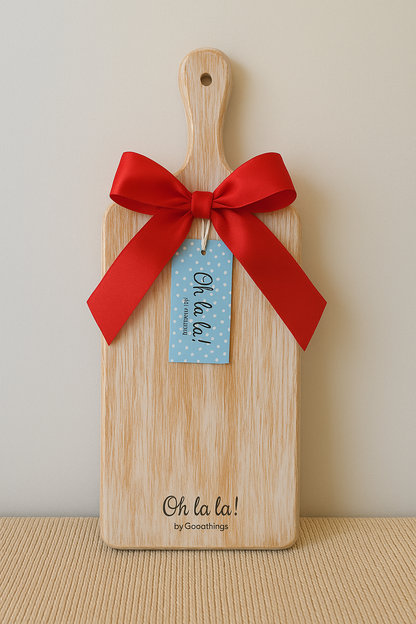 Wooden cutting board with a red ribbon and 'Oh la la!' tag on a beige background