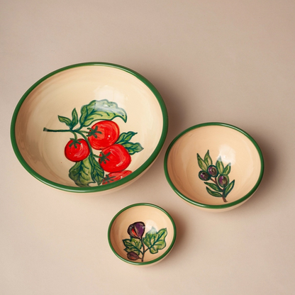 The Huerta Stamped Ceramic Bowls by Eturel Madrid are cream-colored, handmade ceramics with green rims and hand-painted tomatoes and olives, bringing Spanish artisanal charm to your table.