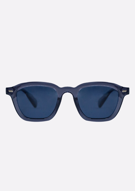 The Oceanides Neda Crystal Blue Sunglasses feature thick recycled plastic frames, dark polarized lenses, and a rectangular shape, shown on a plain light background.