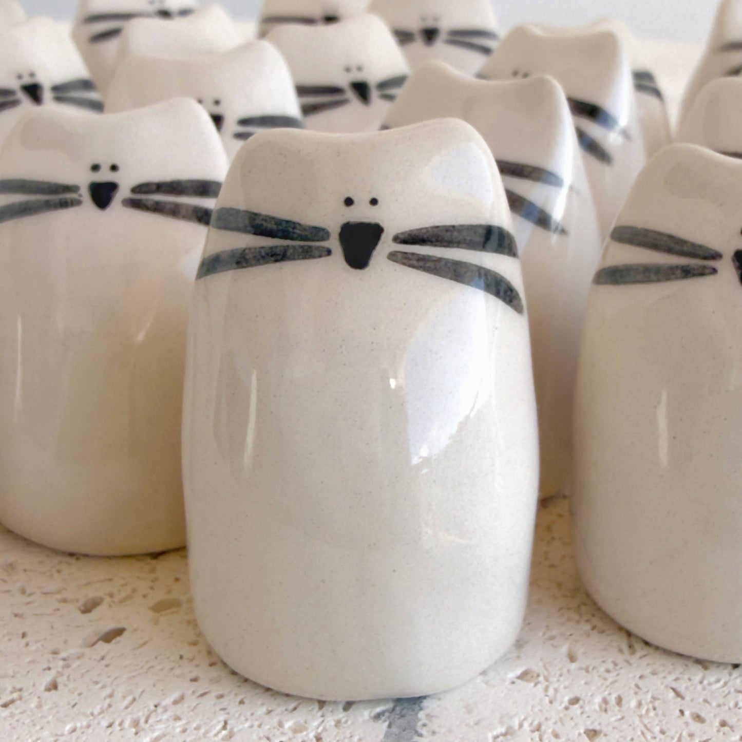Picuru ceramicas' Kitten Amulet of Cuddles features white handmade ceramic cat figurines with simple black details, making a charming friendship or comfort gift.