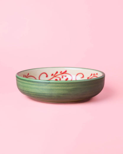 The Alhambra Grater Bowl - Large by Alfar Tierra Cocida is a green ceramic bowl with a white interior featuring red swirls, inspired by handcrafted Spanish kitchenware and shown on a light pink background.