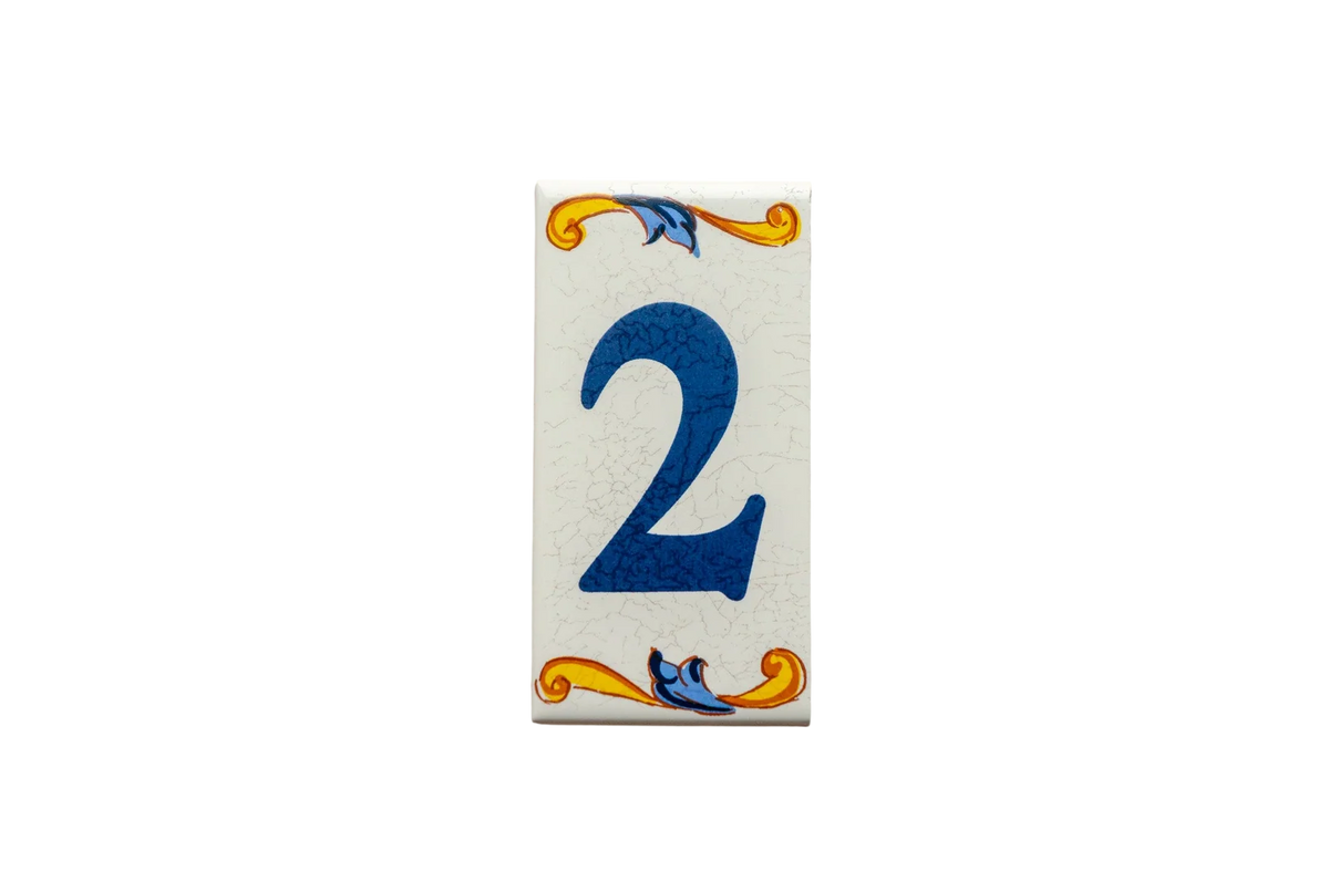 Lisa Croquets Numbers – Ceramic House Number Tiles: rectangular ceramic tile featuring a blue number 2, handcrafted in Spain with decorative yellow and blue scrolls at the top and bottom.