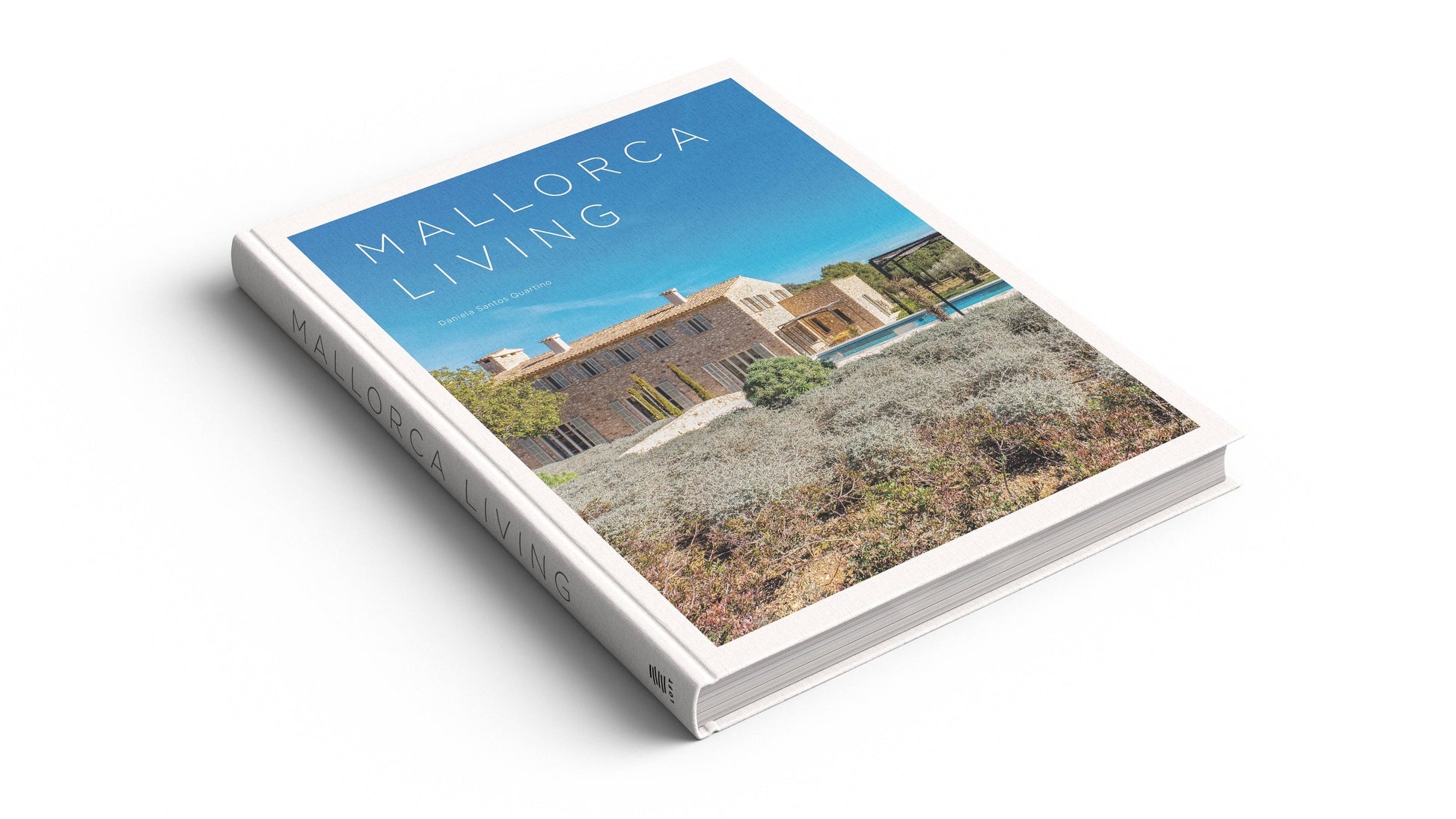 Mallorca Living by Loft Publications is a hardcover coffee table book showcasing Mallorca architecture and Mediterranean-style villas with lush landscaping and pools, featured under a blue sky on a white surface.