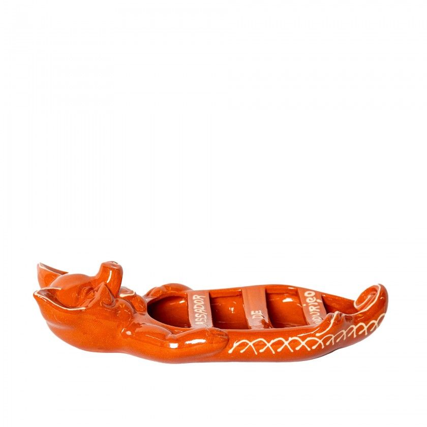 The Terracotta Chorizo Pig Roaster by Ceramica Picas is a ceramic orange canoe-shaped tray with a fox on one end, white side patterns, and two rectangular slots in the middle—ideal for serving or roasting.