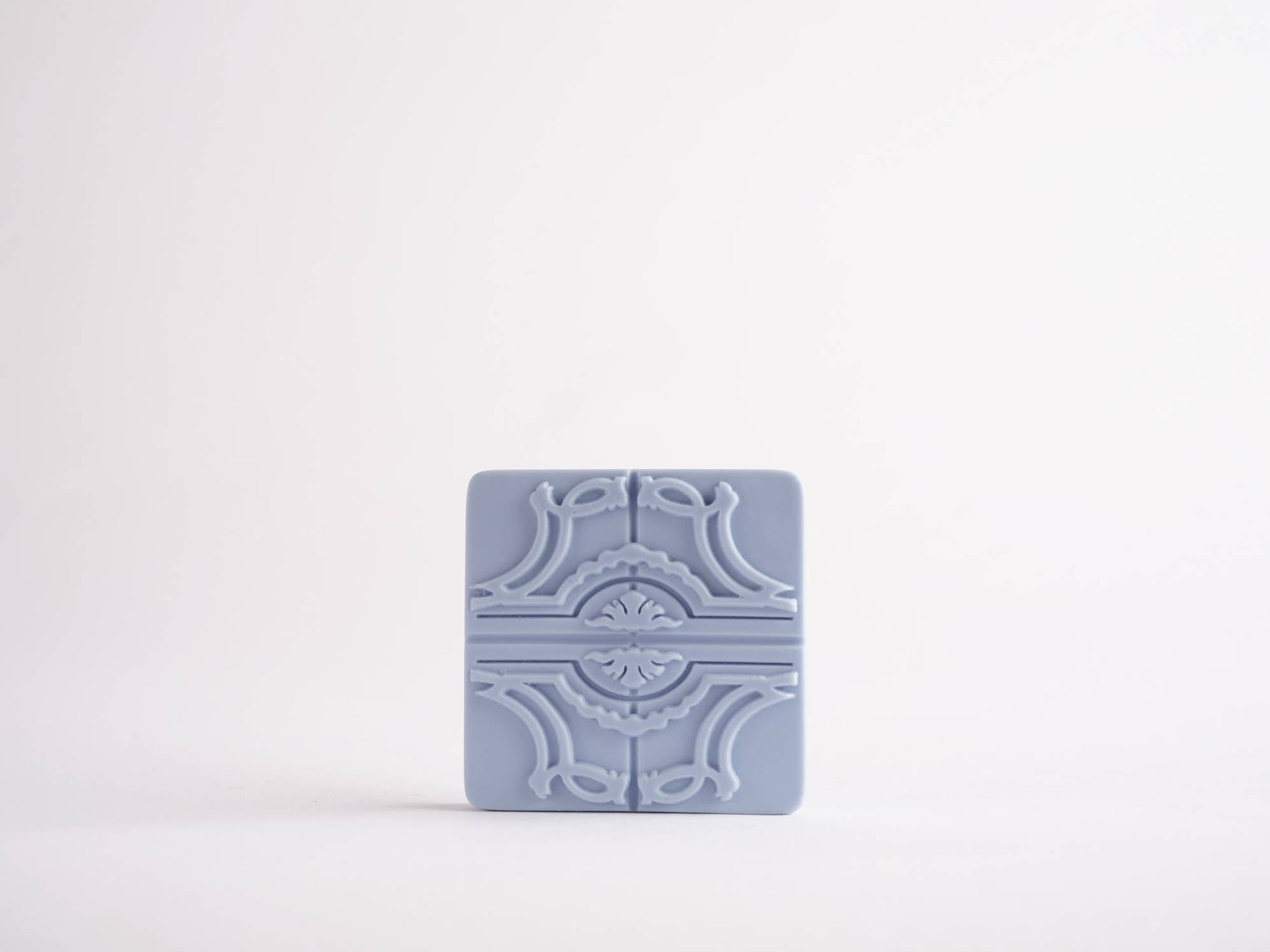 The Sintra Aromatic Tile Magnet by Manulena, inspired by Portugal’s enchanted hills, features a light blue rectangular ceramic design with an ornate symmetrical embossed pattern, displayed on a plain white background.
