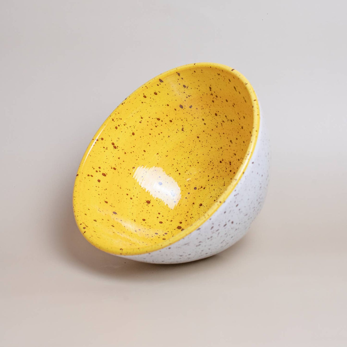 White ceramic bowl with Yellow interior tilted on its side