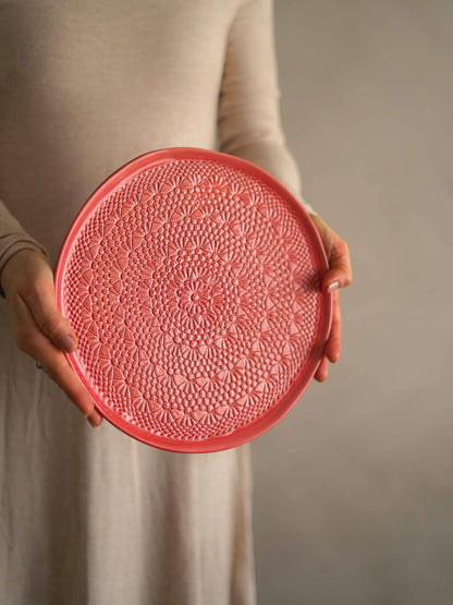 cake plate with crochet stencil print held by woman in rose dress
