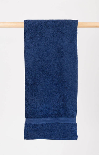 cobalt blue almonda bath towel hanging on a wooden rail